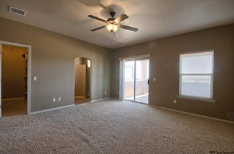 an empty living room with a ceiling fan