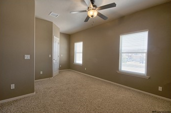an empty living room with a ceiling fan and a window