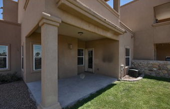 a patio in front of a house with a lawn