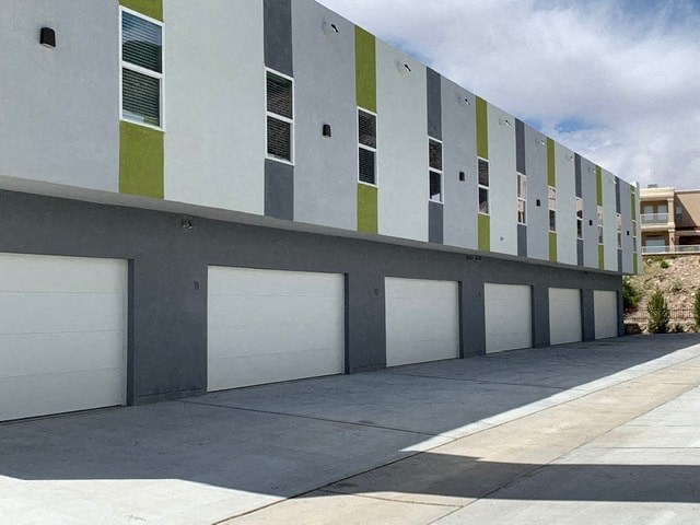 the side of a building with white and green garage doors