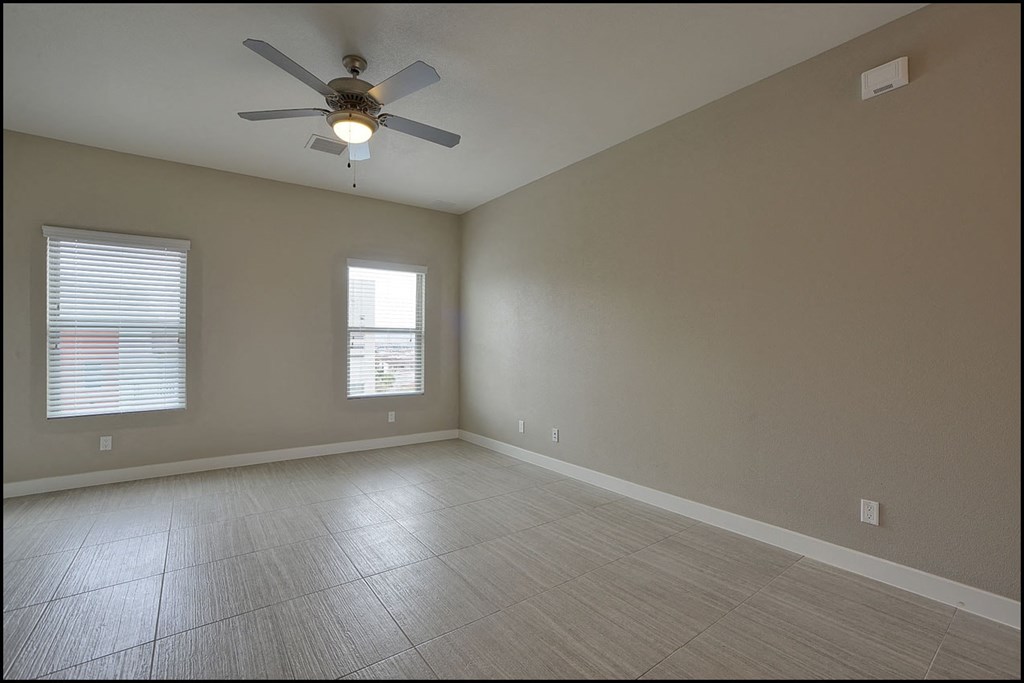 an empty living room with a ceiling fan and a window