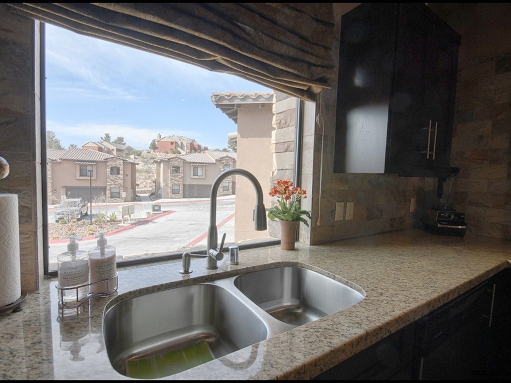 A kitchen sink with a view of a residential area outside the window.