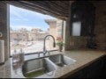A kitchen sink with a window overlooking a street.