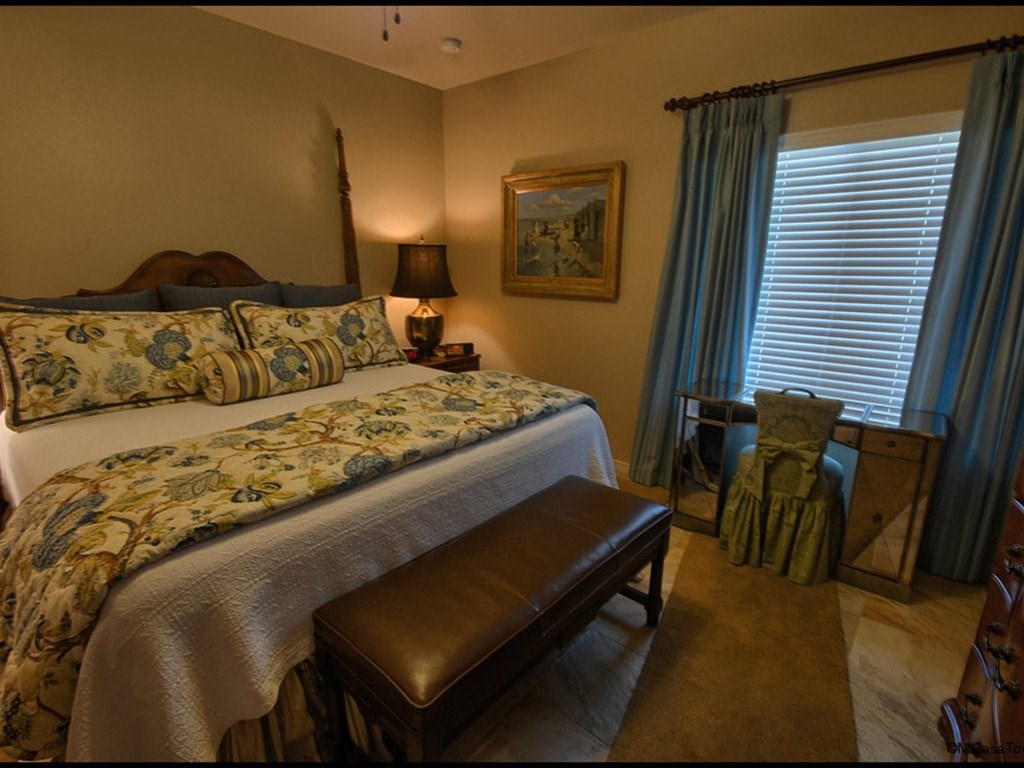 A bedroom with a bed, chair, and window.