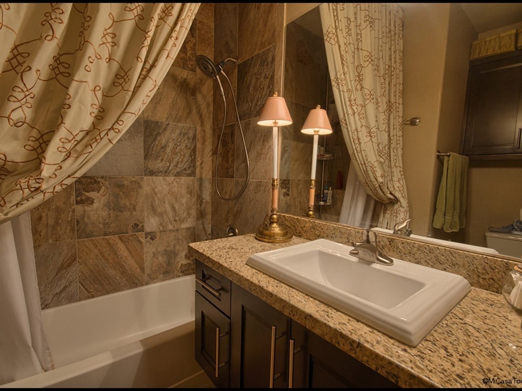 A bathroom with a marble countertop and a white sink.
