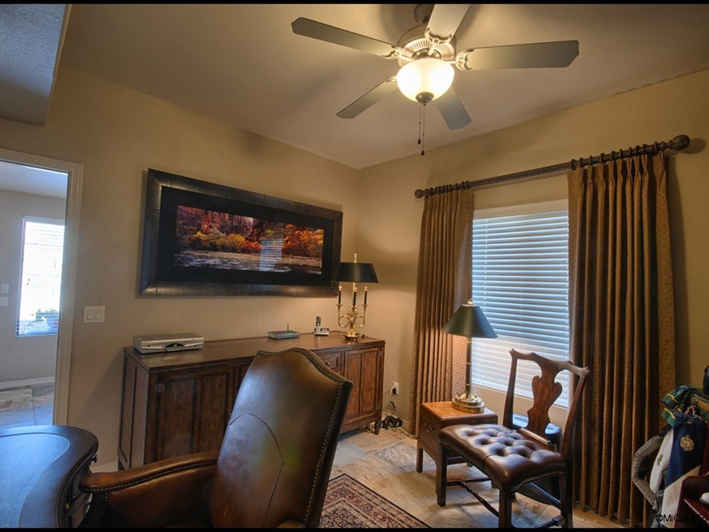 A living room with a brown leather chair and a painting on the wall.