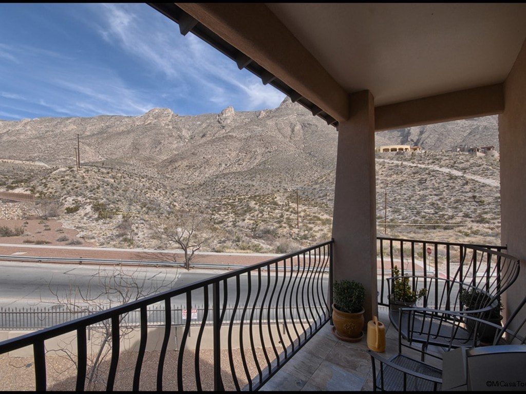 A balcony with a metal railing overlooks a mountainous landscape.