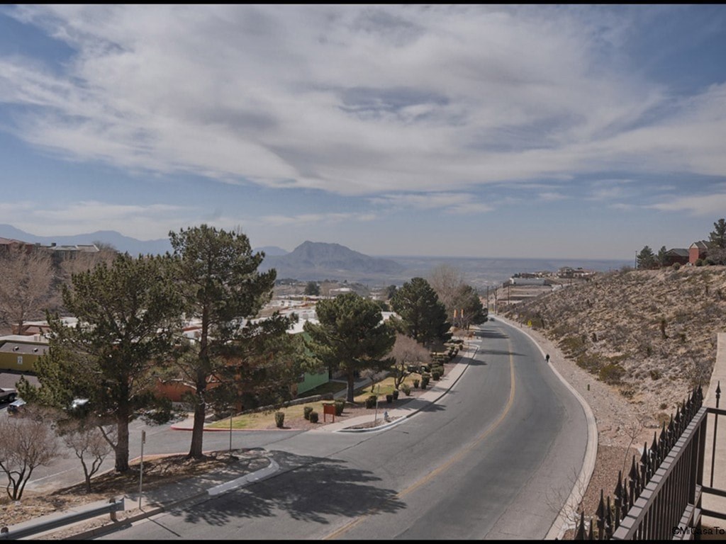 A road with a curve leading to a mountain range.