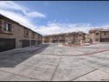 A parking lot with a few cars and a building in the background.