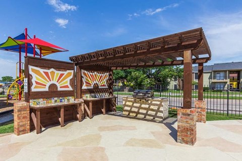 A playground with a wooden structure and a colorful umbrella.