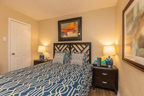 A bedroom with a patterned bedspread and two lamps on either side of the bed.