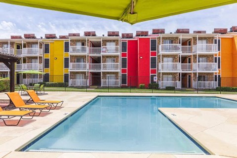 A swimming pool is surrounded by sun loungers and chairs.