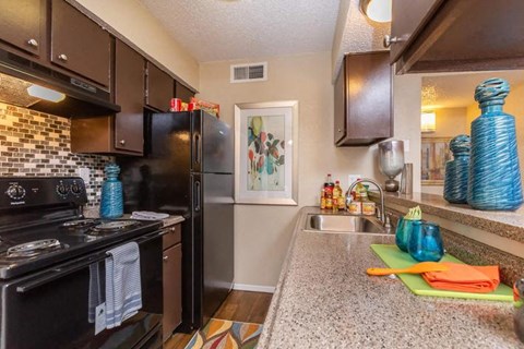 A kitchen with black appliances and brown cabinets.