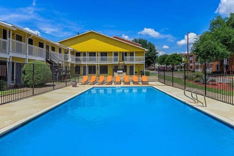 A swimming pool in front of a yellow building.