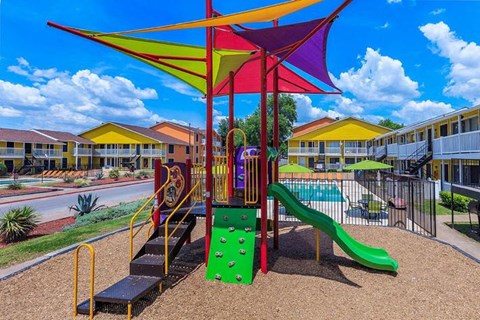 A playground with a green slide and a red and yellow structure.