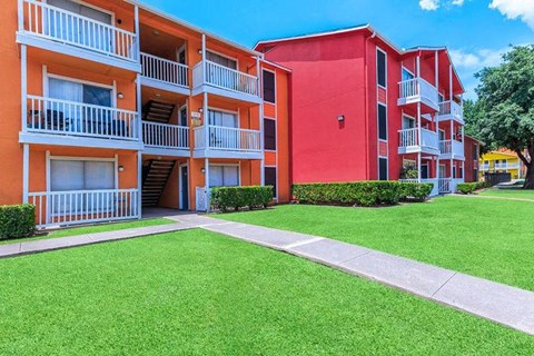 A red and orange apartment building with green grass in front.