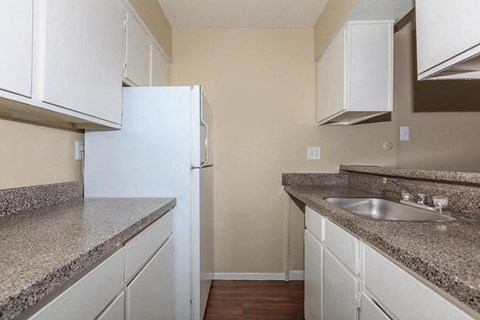 A kitchen with white cabinets and a granite countertop.
