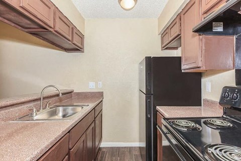 A kitchen with a black stove top oven and a black refrigerator.
