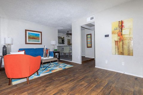 A living room with a red chair and a painting on the wall.