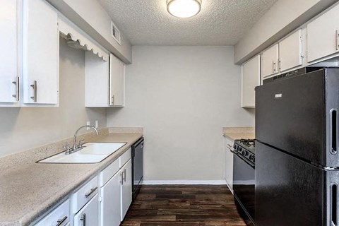 A kitchen with a black refrigerator and white cabinets.