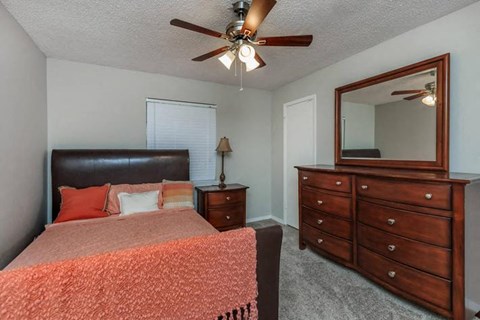 A bedroom with a bed, dresser, and mirror.