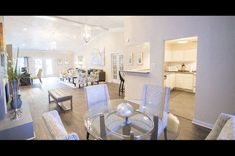 A modern living room with a glass table and grey chairs.