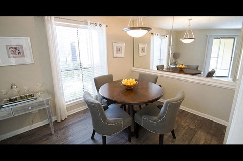 A dining room with a round table and grey chairs.
