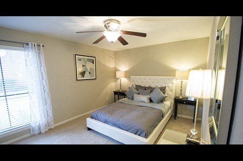 A bedroom with a bed, nightstand, and a ceiling fan.
