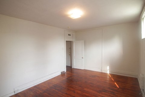 an empty living room with white walls and a wooden floor