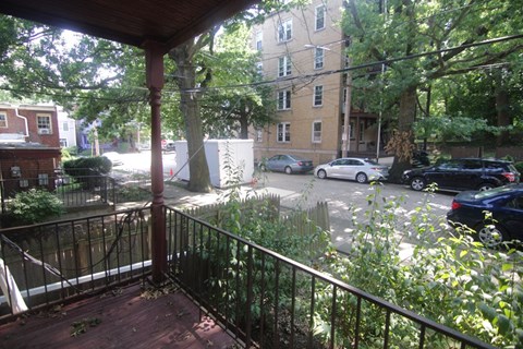 A view from a balcony looking out at a street with cars and buildings.