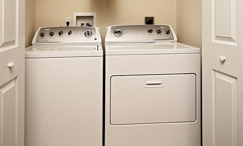 two washes and dryers in a kitchen with white doors