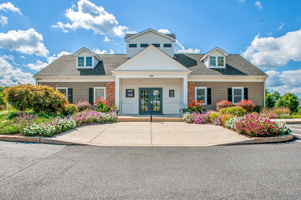 the front of a house with flowers and a driveway