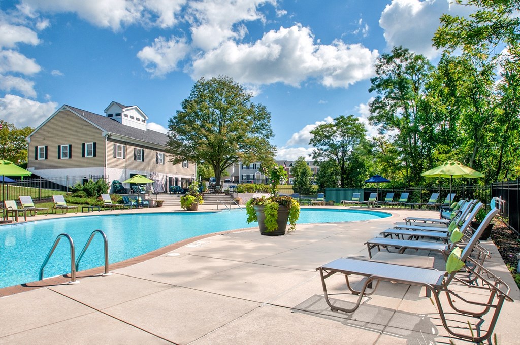 a swimming pool with chairs and a building in the background
