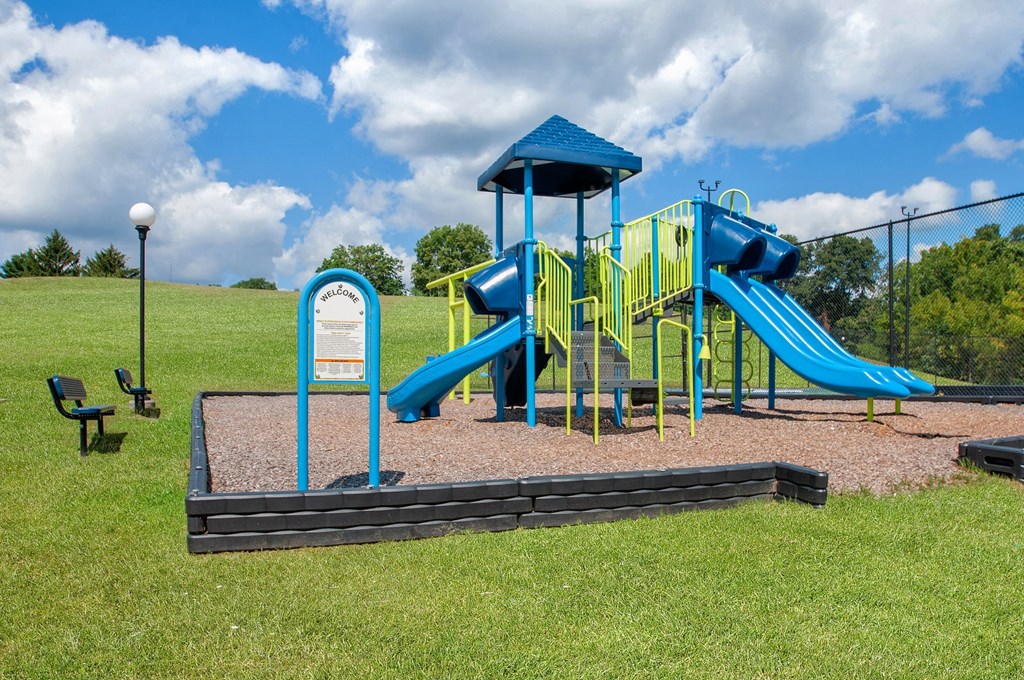 a playground with a blue playset and a swing set