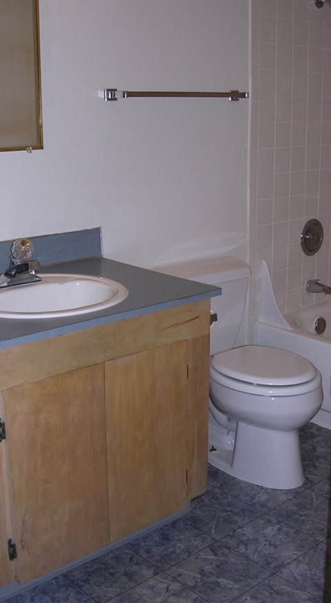 A white toilet sits in a bathroom next to a sink and bathtub.