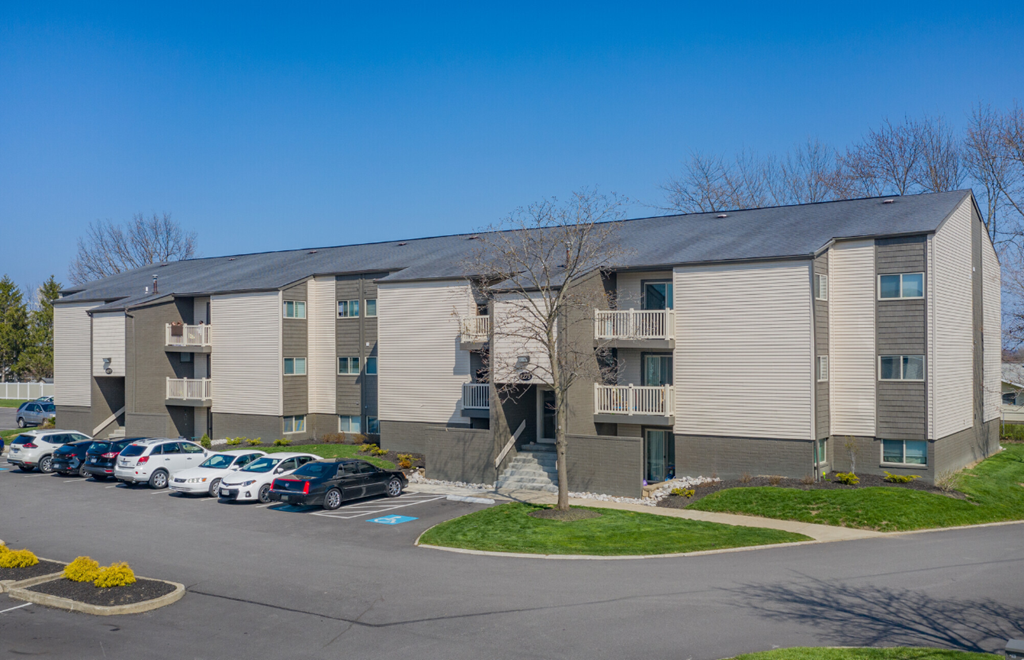 A parking lot in front of a building with cars parked.