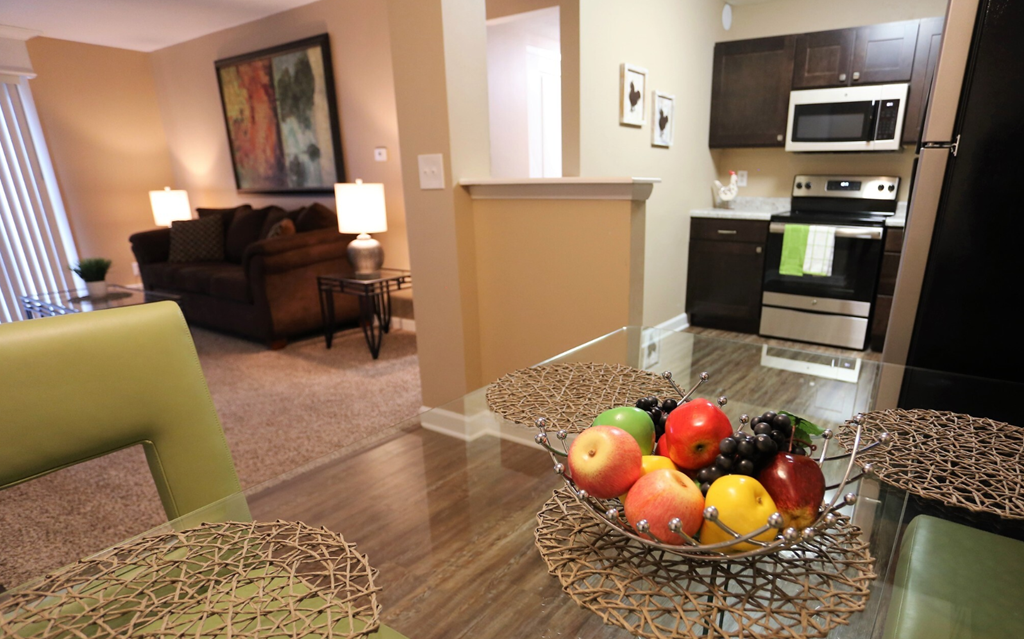 A bowl of fruit sits on a table in a well-lit room.