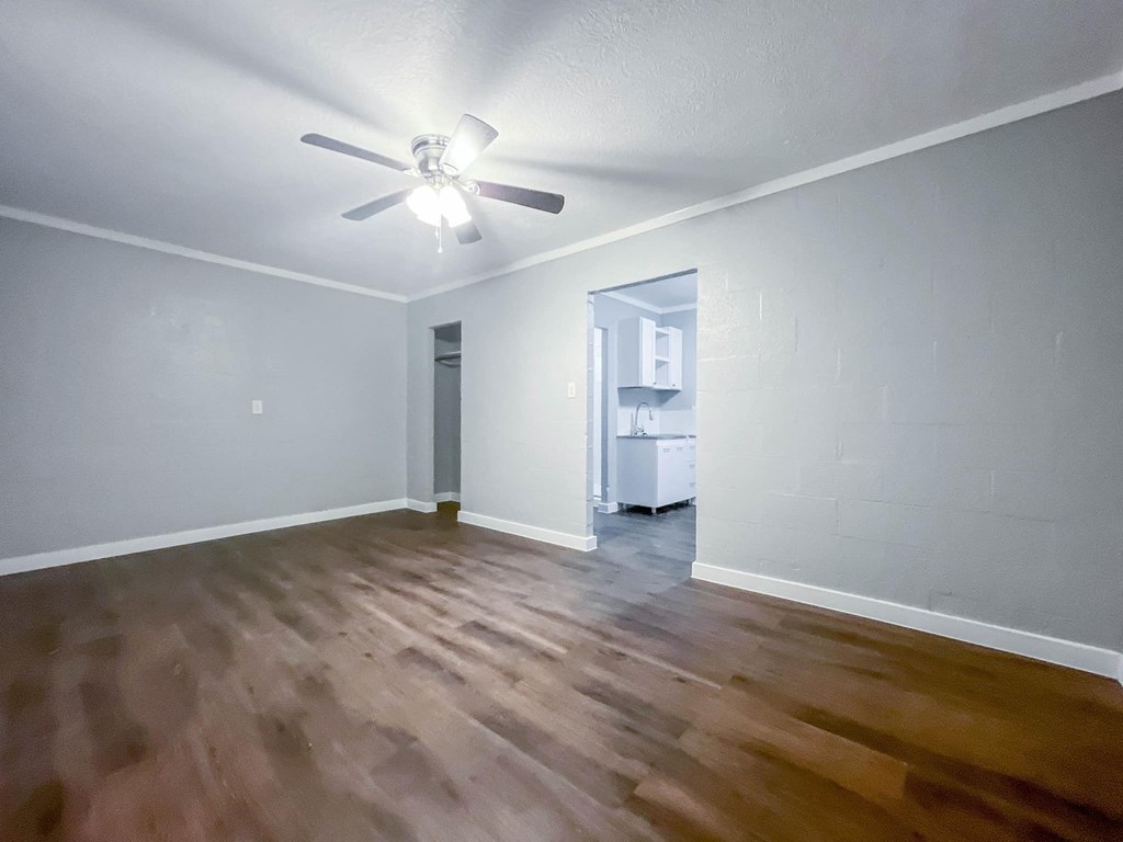 an empty living room with hardwood flooring and a ceiling fan