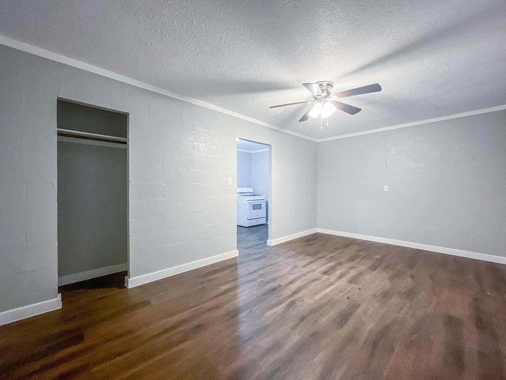 an empty living room with wood flooring and a ceiling fan