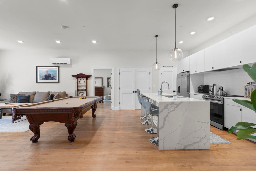 a living room with a pool table and a kitchen