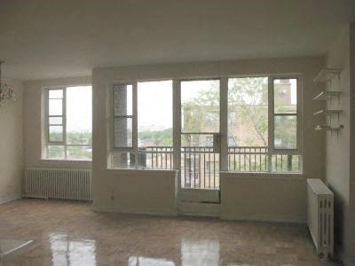 an empty living room with windows and a radiator