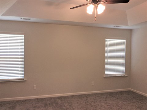 a living room with a ceiling fan and two windows