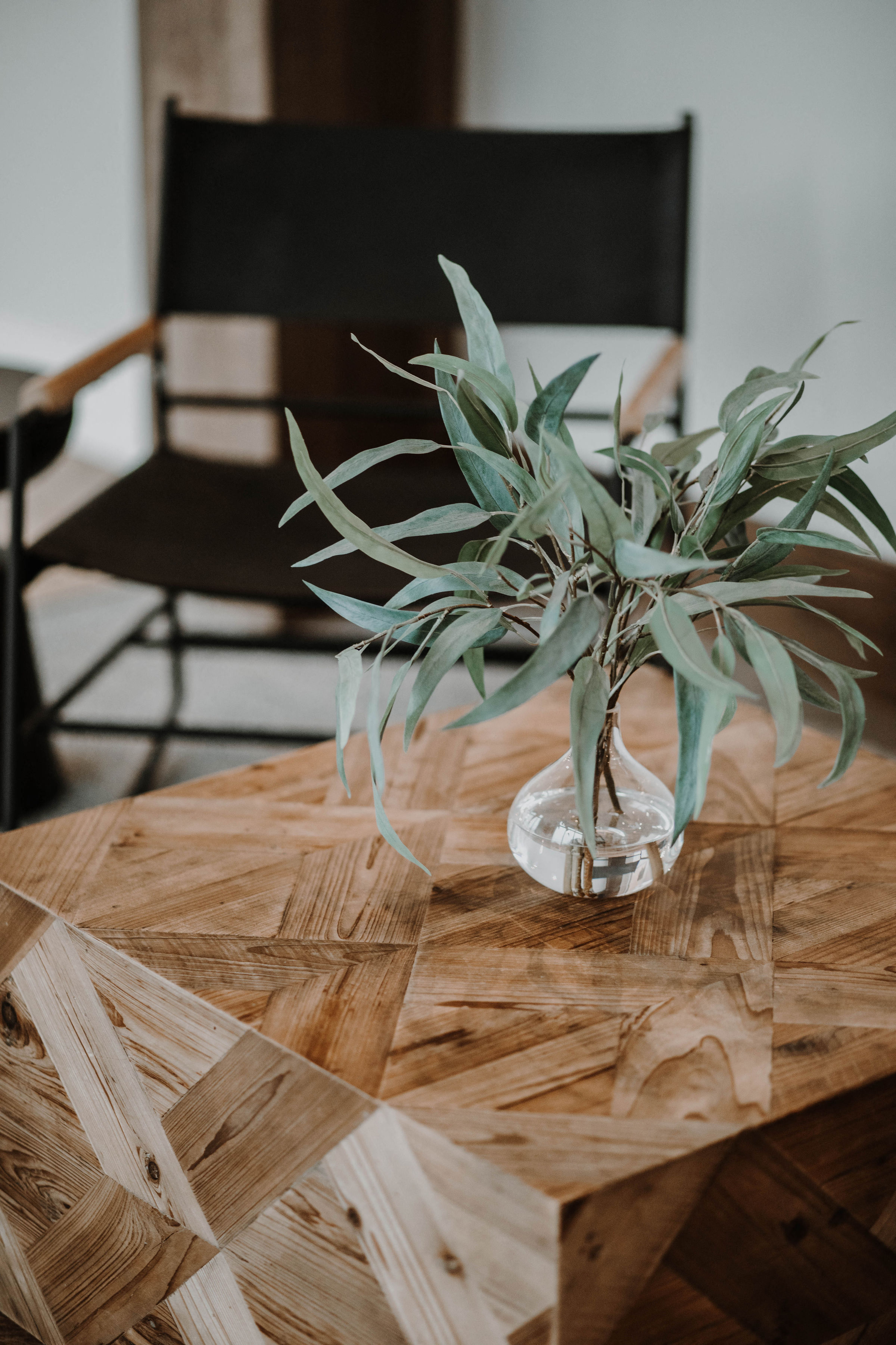 a wooden table with a plant in a glass vase on it