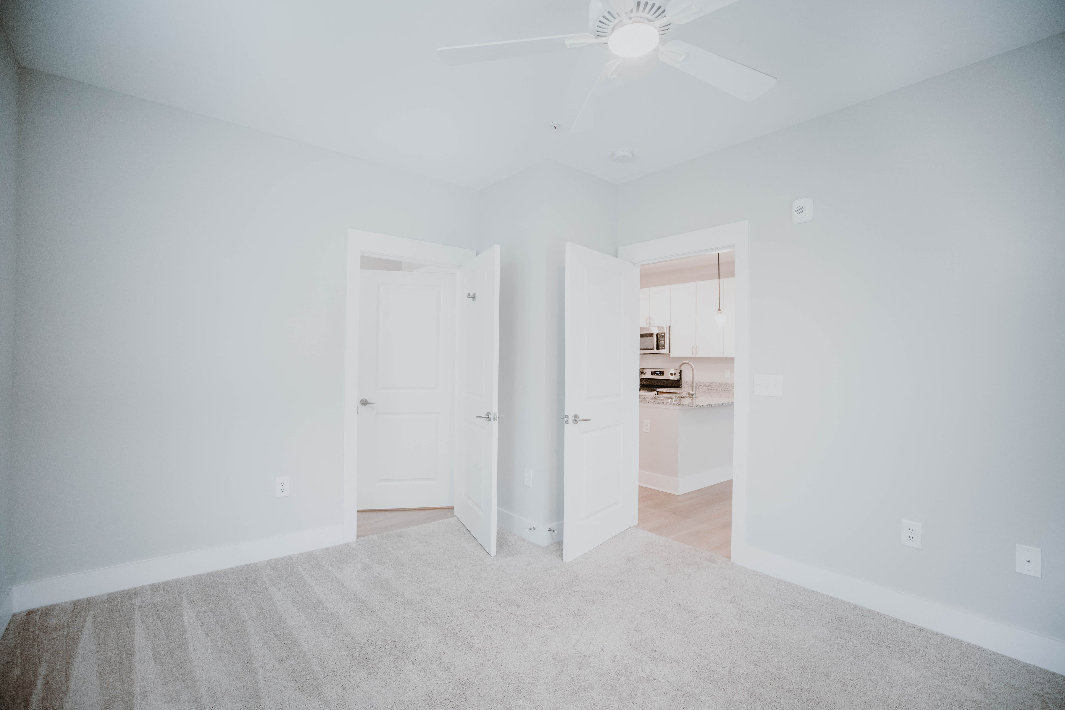 an empty living room with white walls and a ceiling fan