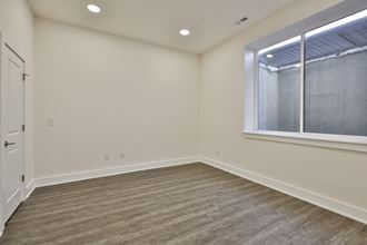 an empty living room with a large window and wood flooring