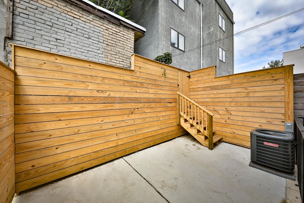 a wooden fence in front of a house with a trash can