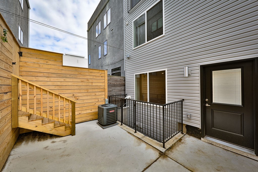 the patio of a house with a black door and a wooden fence