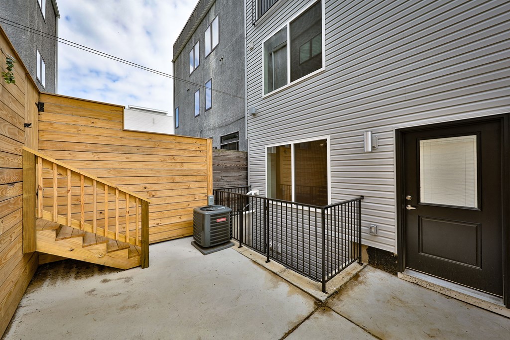 the patio of a house with a black door and a wooden fence