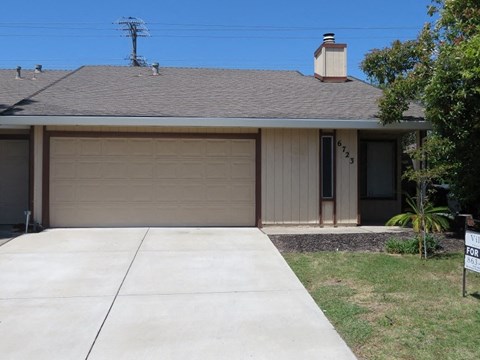 A house with a garage door and a sign in front of it.