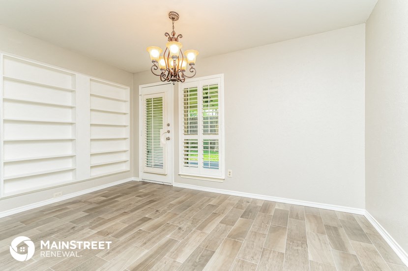 a living room with white walls and wood floors and a chandelier
